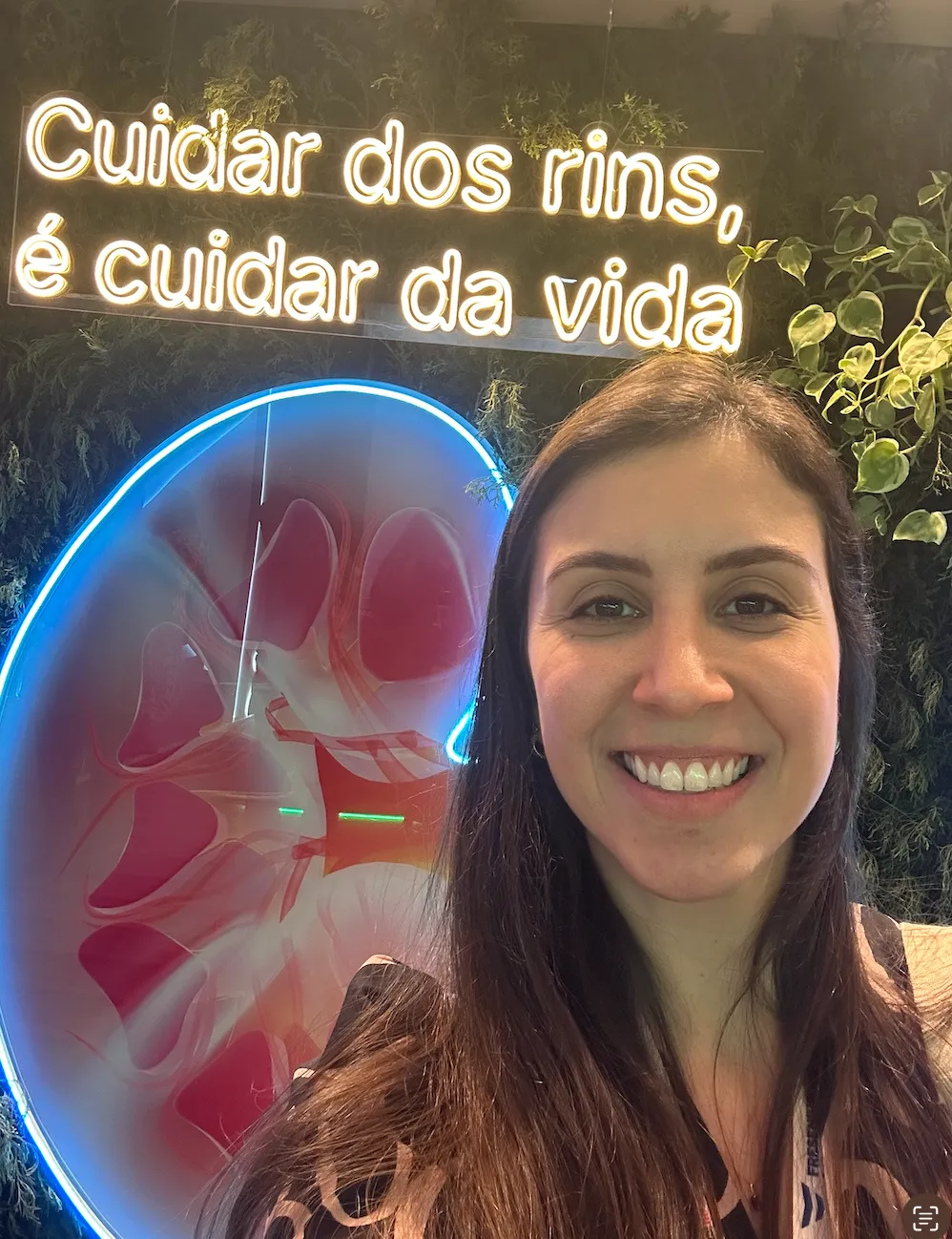 Dra. Marina diante de um letreiro luminoso: “Cuidar dos rins, é cuidar da vida”